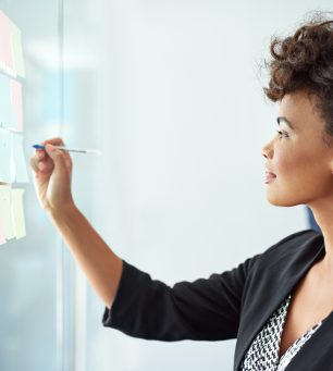 Shot of a businesswoman making notes on a glass board